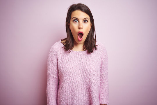 Young beautiful brunette woman wearing a sweater over pink isolated background afraid and shocked with surprise expression, fear and excited face.