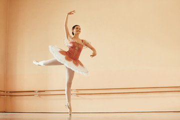 Full length of smiling ballerina dancing in ballet studio.