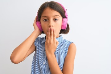 Beautiful child girl listening to music using headphones over isolated white background cover mouth with hand shocked with shame for mistake, expression of fear, scared in silence, secret concept