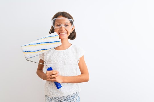 Beautiful child girl holding painting roller standing over isolated white background with a happy face standing and smiling with a confident smile showing teeth