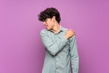 Fototapeta na wymiar Young man over isolated purple wall suffering from pain in shoulder for having made an effort