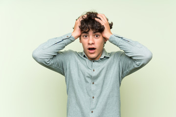 Young man over isolated green wall with surprise facial expression