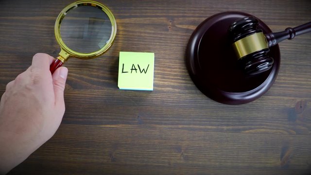 Law. Rules and truth concept. Man's hand holding magnifying glass