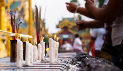 Burning candles and incense at a colourful Buddhist temple in Myanmar during day light time.