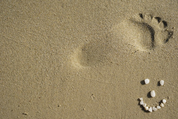 Fototapeta na wymiar Footprint in the sand with a smiley 