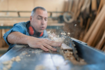 A carpenter works on woodworking the machine tool. Carpenter working on woodworking machines in carpentry shop.