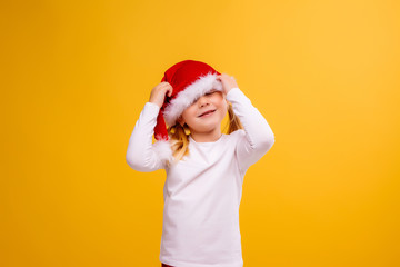 little blonde girl in Santa hat on yellow isolate background, Christmas and new year concept. space for text