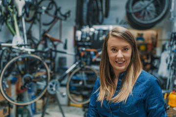 Fototapeta na wymiar Portrait of young female mechanic in bicycle store