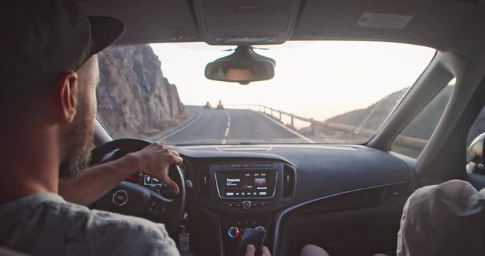 Man hipster driving his modern car on highway. Close-up. Young couple traveling in car through mountains landscape on vacation roadtrip.