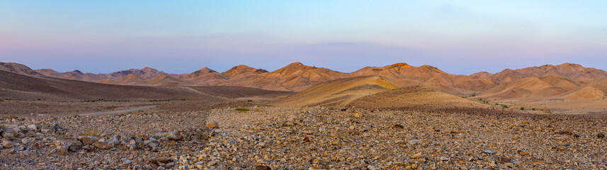 Panoramic view of stone desert land with desertic arid mountains and rocks in the background - 303222182