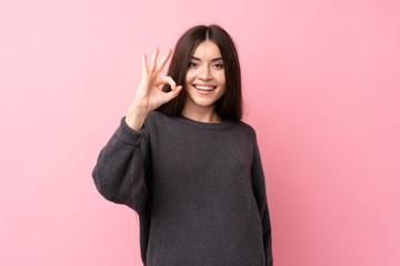 Young woman over isolated pink background showing ok sign with fingers