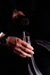 Sommelier feeling with red wine decanter on a black background Close up