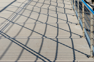 Concrete walkway with railing shadows casting on the floor