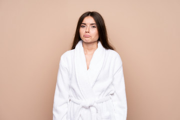 Young girl in a bathrobe over isolated background sad