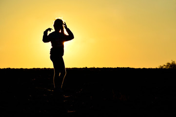 teenager girl posing in a field on a background of golden sunset