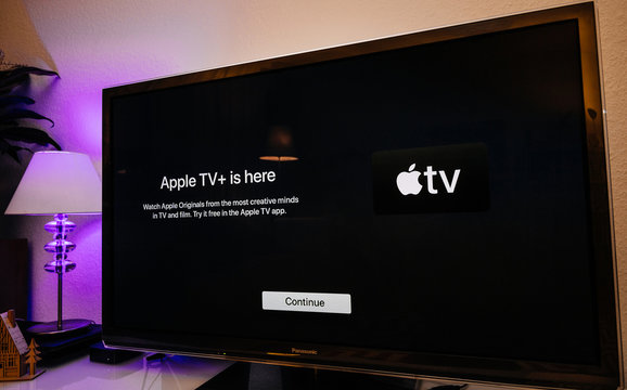 Paris, France - Nov 1, 2019: Side view of Apple TV plus is here message on living room display with try for free continue button - wide Panasonic plasma OLED tv set