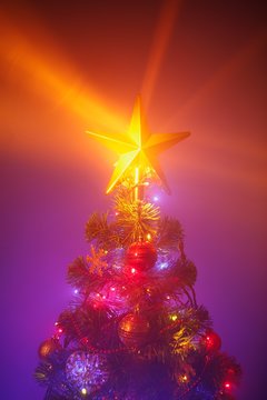 Christmas tree with festive lights, purple background with mist