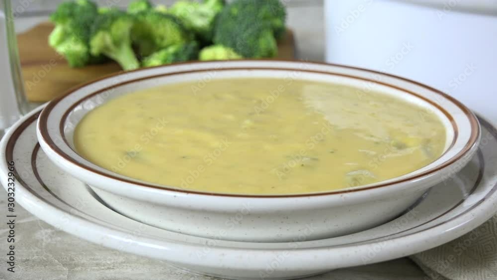 Poster serving and eating a bowl of broccoli cheese soup with garlic croutons