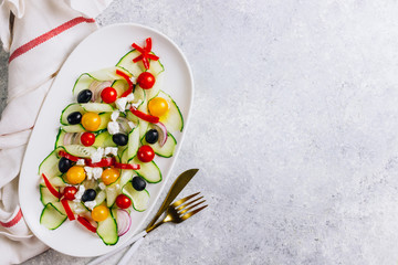 Vegetable Greek salad with tomatoes, feta cheese, onions, cucumber and olives. christmas tree shape. Served on white plate on the festive table. Top view. Flat lay. Copy space