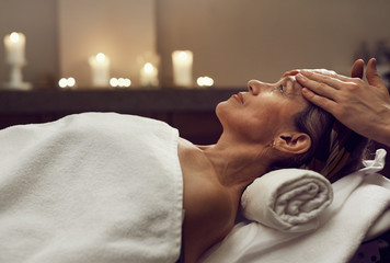 Side view portrait of elegant senior woman enjoying facial massage at luxury SPA center, copy space