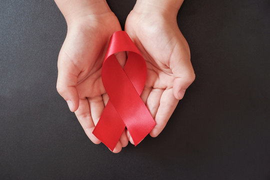 Hands Holding Red Ribbon On Black Background, Hiv Awareness Concept, World AIDS Day, World Hypertension Day