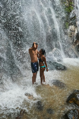 Boyfriends under waterfall, on the bottom of rocks and river.