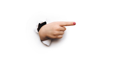 The forefinger points to the right side. White background. Place for advertising. Copy space. The child's hand came out into the torn paper hole.
