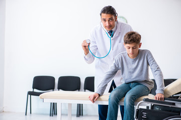 Young male doctor pediatrist and boy in wheel-chair