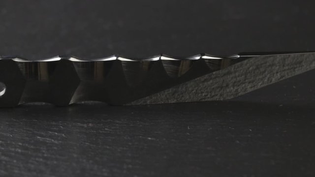 Custom hand crafted japanese kiridashi knife on the turning slate board table. Polished metal surface with texture