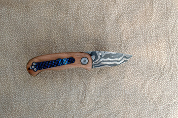 Pocket clip on back side of damascus liner lock folding knife. Bokeh