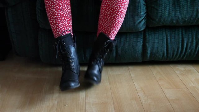 foot view of taking off black winter or combat boots at home on the couch 