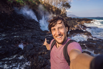 Smiling guy in the sea spray on the rocks