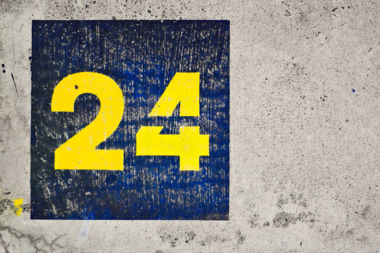Number 24, twenty-four, yellow and blue painted on a concrete background.