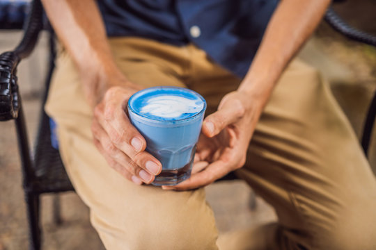 Young man having a mediterranean breakfast seated at sofa and drinks Trendy drink: Blue latte. Hot butterfly pea latte or blue spirulina latte