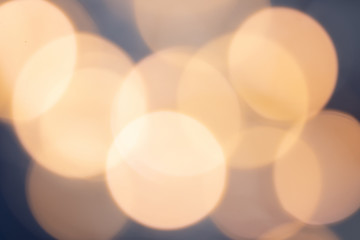 Festive mood: large circles of bokeh of warm white light on a blue background with blur