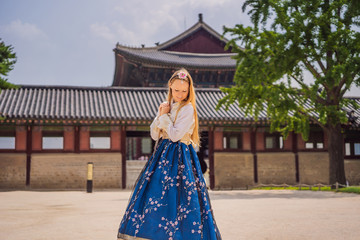 Fototapeta premium Young caucasian female tourist in hanbok national korean dress. Travel to Korea concept. National Korean clothing. Entertainment for tourists - trying on national Korean clothing