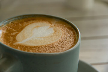 Close up hot coffee with leaf-shaped cream.