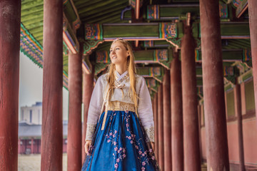 Young caucasian female tourist in hanbok national korean dress at Korean palace. Travel to Korea...