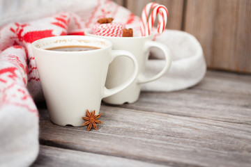 Cup of hot black coffee, knitted sweater with deer, candy cane and spices on wooden background. Winter background