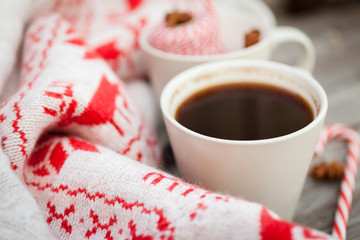 Obraz na płótnie Canvas Cup of hot black coffee, knitted sweater with deer, candy cane and spices on wooden background. Winter background