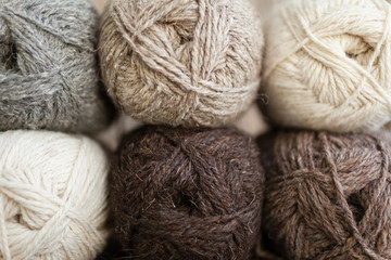 Yarn skeins for handmade. Beige, brown, gray and white balls of yarn. Wooden background, natural wool knitting background