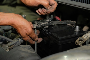 technician changing car battery in auto repair garage