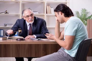 Young man visiting experienced male lawyer