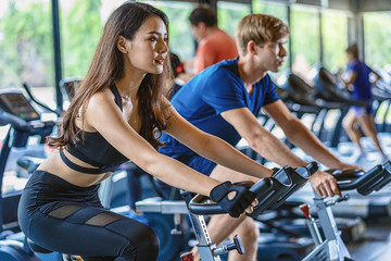 Fototapeta na wymiar Couple young diversity working out in gym fitness sport complex, workout working out bicycle and cardio, posture position, spinning class, sports and healthcare concept