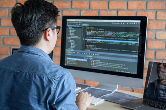 Young Professional programmer working at developing programming and website working in a software develop company office, writing codes and typing data code, Programming with HTML, PHP and javascript