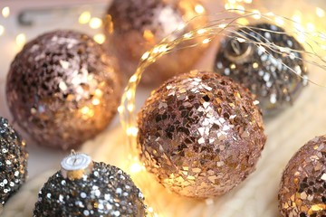 Christmas and New Year winter festive background.Pink and gray balls close-up for Christmas tree decor and shining garland on a white knitted scarf.Phone christmas wallpaper.Winter holidays. 