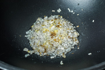 Sliced white onions in oil for frying in cast iron cauldron for pilaf.