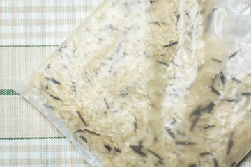 Transparent bag with mixture of white and brown rice on kitchen table.