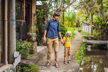 Father and son tourists in Bali walks along the narrow cozy streets of Ubud. Bali is a popular...