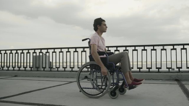 Man with paralysis of legs muscles is sitting in invalid carriage and riding. Ride from Left to Right
